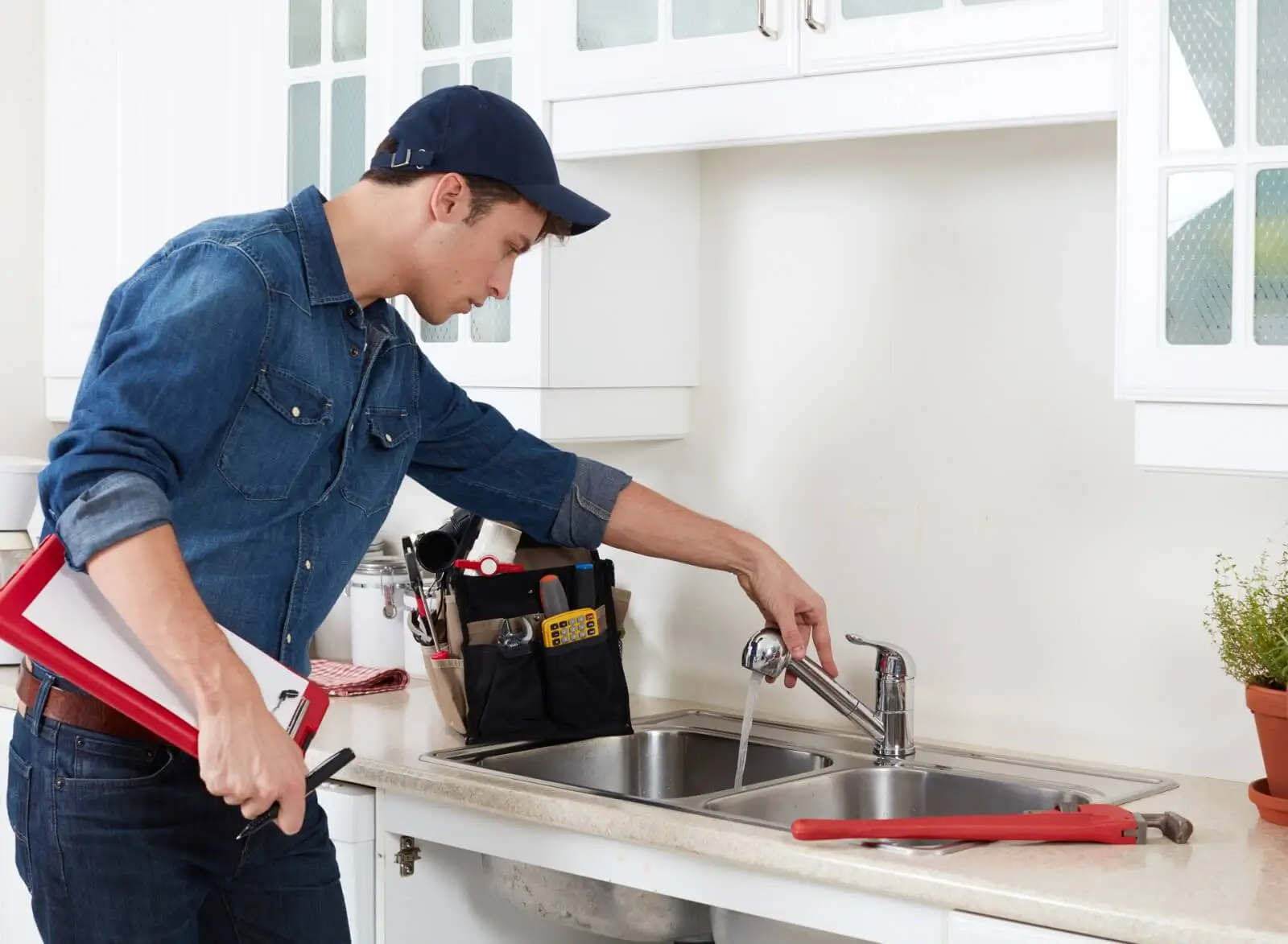 Plumber fixing kitchen sink faucet.