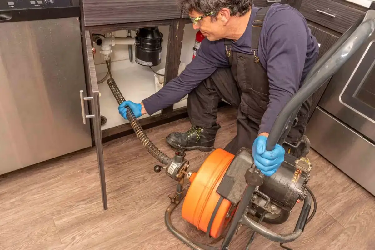 Plumber using drain cleaning equipment.