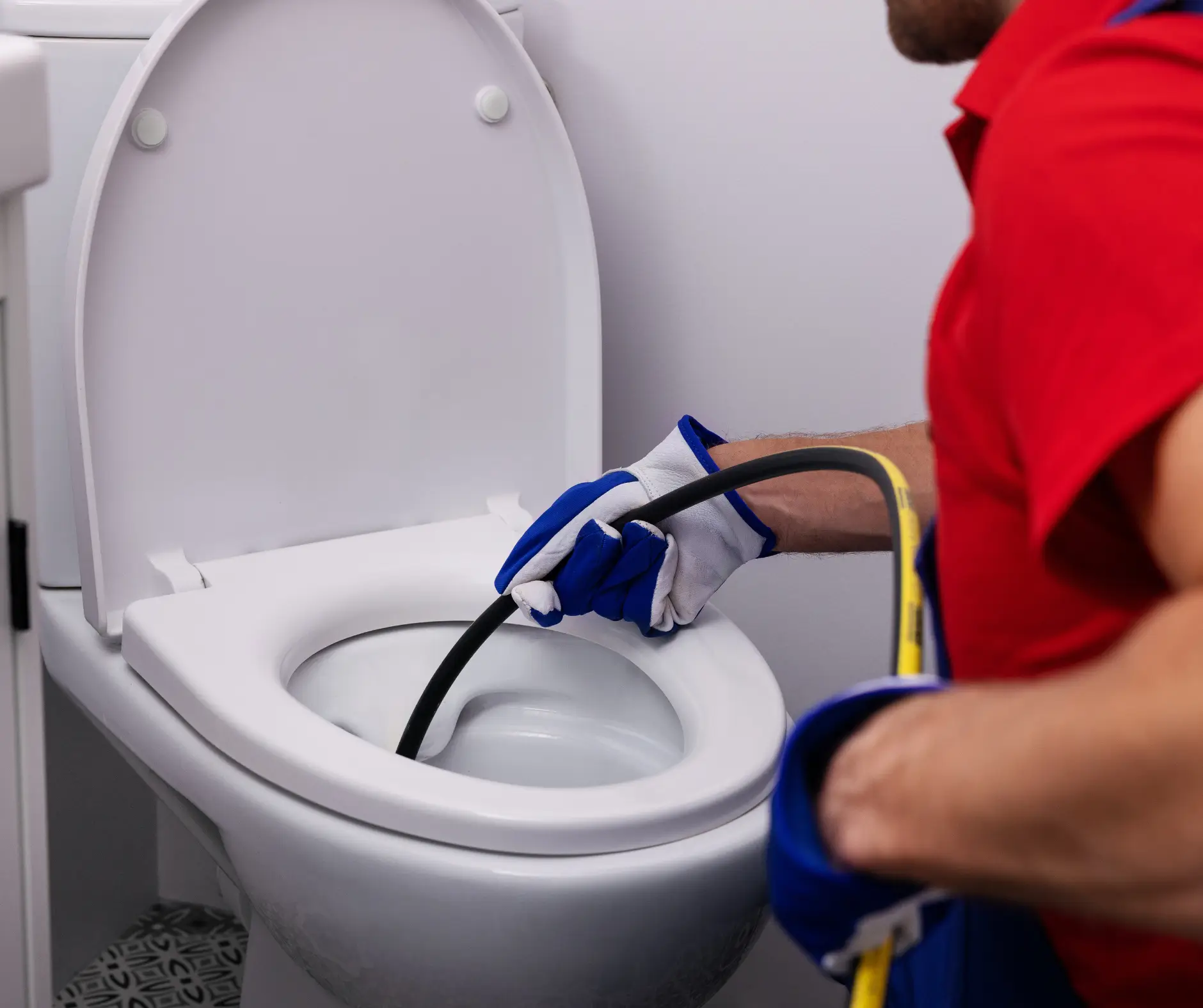 plumber unclogging blocked toilet with hydro jetting at home bathroom