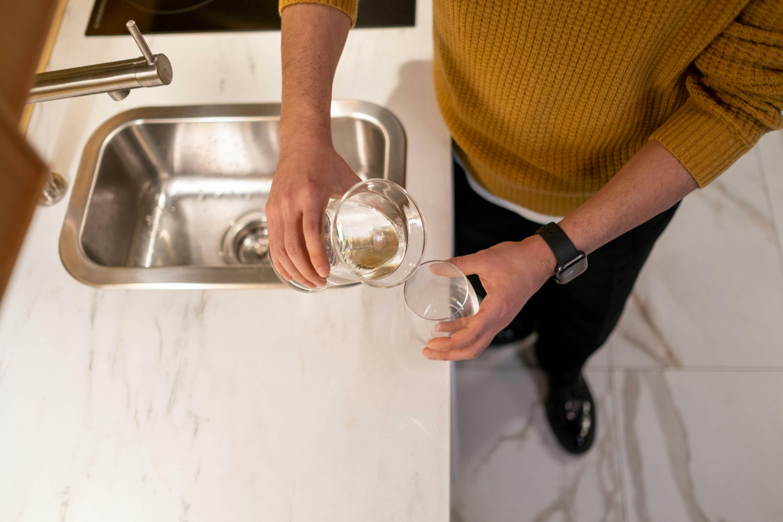 A Person in a Sweater Pouring Water in a Glass