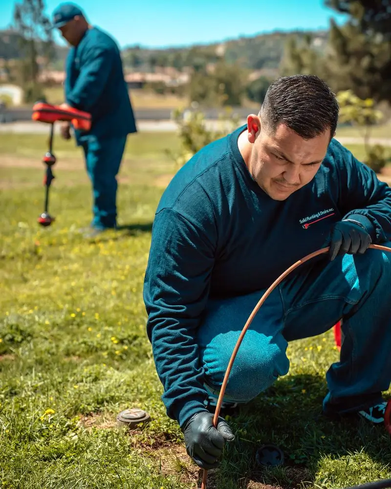 Solid Plumbing & Drains technician performing plumbing work outdoors