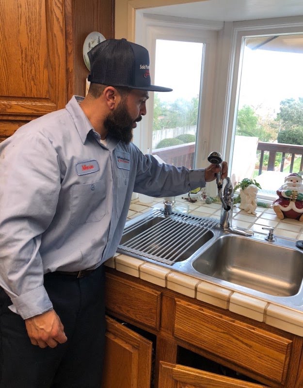 Residential plumber servicing a kitchen sink and faucet