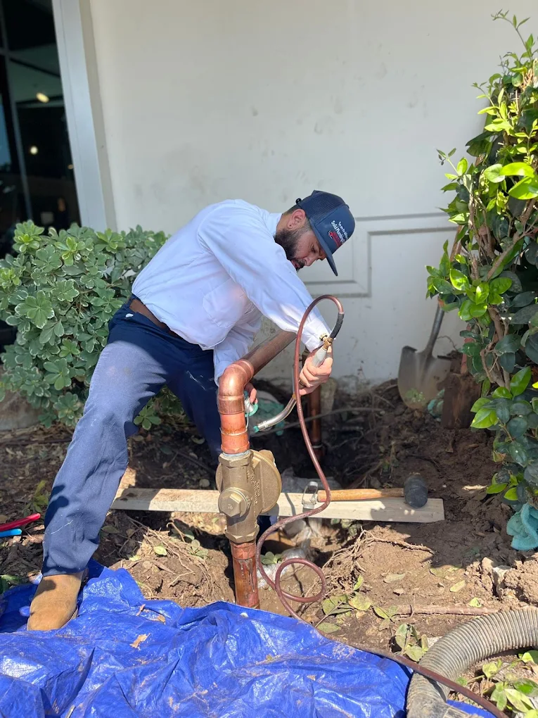 Plumber repairing an outdoor residential plumbing line and valve