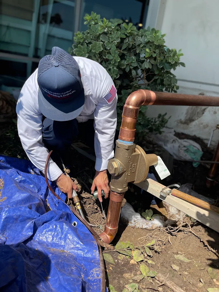 Solid Plumbing & Drains technician working on an outdoor copper water line in San Diego