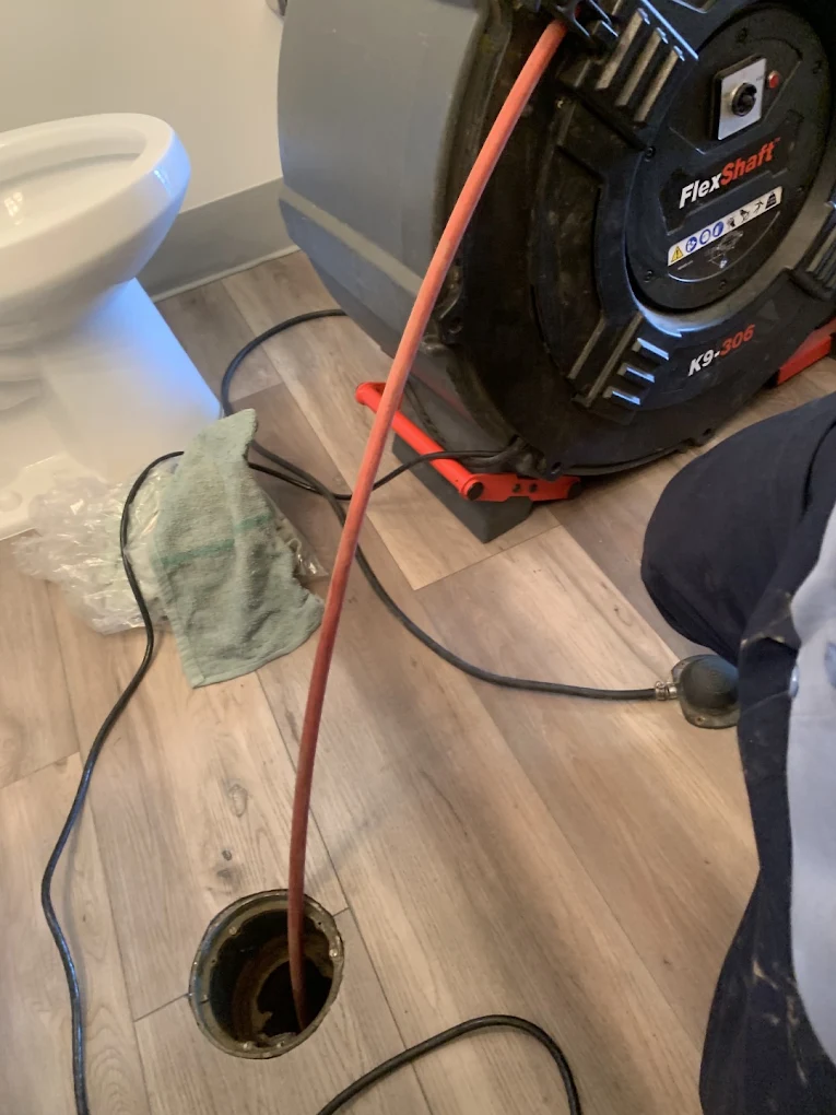 Plumber using a FlexShaft machine to clean a residential drain line in San Diego
