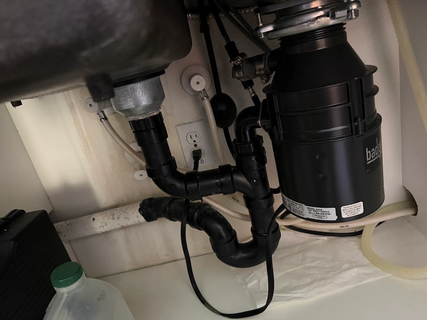 Under-sink kitchen plumbing with garbage disposal and drain piping in San Diego