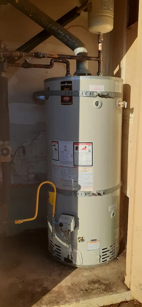 Existing residential tank-style water heater installed in a utility closet with visible plumbing and gas connections.