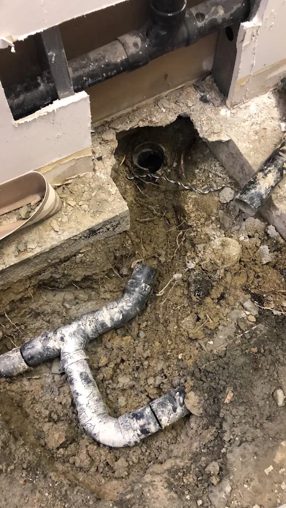 Excavated underground drain piping with exposed and disconnected pipe sections during sewer line repair work.